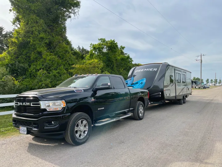 RV rental ready: Black truck towing a travel trailer and kayaks for an outdoor adventure.. Keystone RV Bullet Premier Ultra 2020