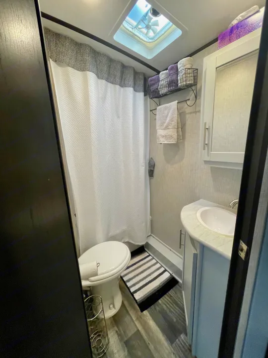 Step inside this clean, functional RV rental bathroom featuring a toilet, shower, sink, and neatly organized towels.. Keystone RV Bullet Premier Ultra 2020