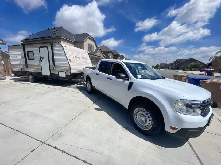 White truck towing Aspen Trail RV rental with solar panels on driveway.. Aspen Trail LE 2021