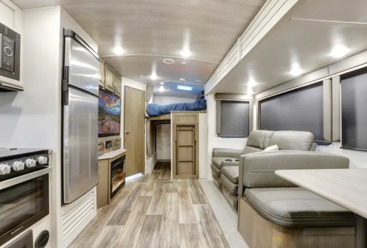 Explore this inviting RV rental interior featuring a kitchen, living area with recliners, and bunk beds for your next adventure.. Keystone RV Cougar 2021