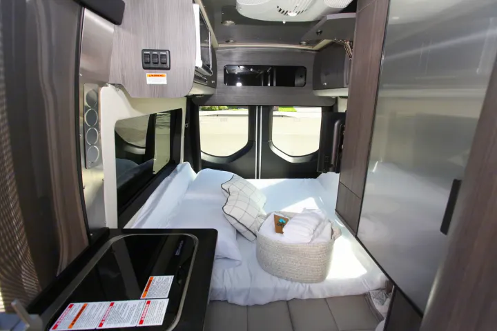Step inside this modern RV rental showcasing a compact kitchen, comfy bed, and clever storage solutions for your adventure.. Airstream Interstate 2021