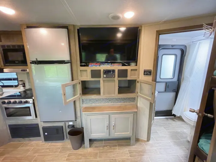 Modern RV rental interior featuring a full kitchen with fridge/stove, entertainment center with TV, stereo, and a bathroom. Great amenities.. Forest River Palomino Puma 2019