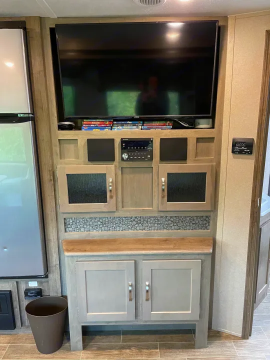 Inside an RV rental: a modern entertainment center with TV, stereo, speakers, media, and cabinetry. Enjoy comfort on the road.. Forest River Palomino Puma 2019