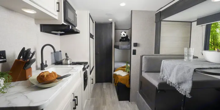 Cozy RV rental interior: well-equipped kitchen, bunk beds with a panda, and bright dining space for your next adventure.. Jayco slx 2023