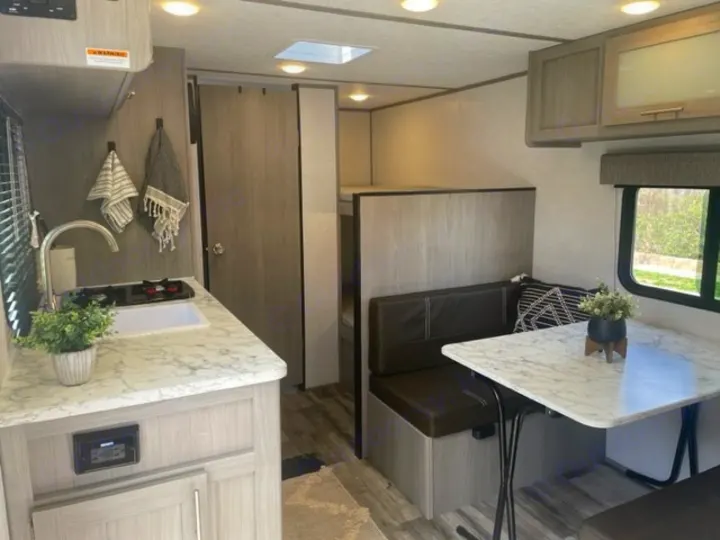Cozy rv rental interior featuring a modern kitchen, dining area, and bunk beds for your travels.. Dutchmen Coleman Lantern LT 2023
