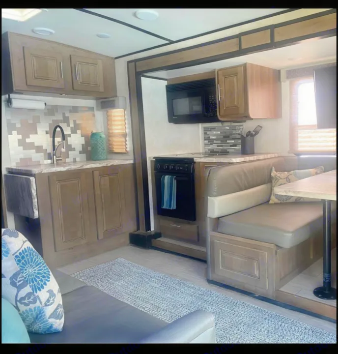 An inviting RV rental interior showcasing a modern kitchen with stove, microwave, and a comfortable dinette area.. FR3 FR3 Motorhome 2020