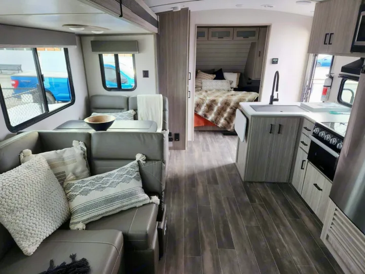 Modern RV rental interior showcasing a comfortable living area, full kitchen, and private bedroom beyond.. Keystone RV Passport GT 2022