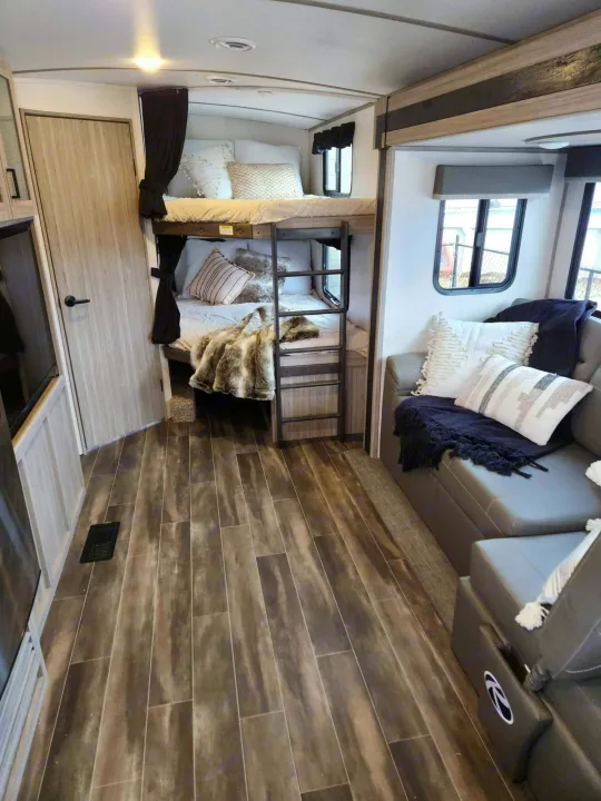 Inside this RV rental: a modern interior with comfortable bunk beds, a sofa living area with soft cushions, and durable wood-style flooring.. Keystone RV Passport GT 2022