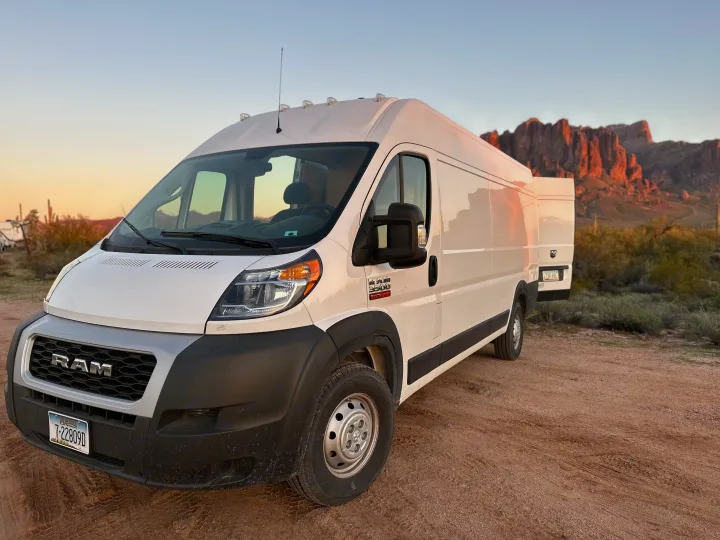 White Ram ProMaster camper van for rv rental, parked in a desert landscape with mountains at sunset.. Custom Promaster 2021 2021