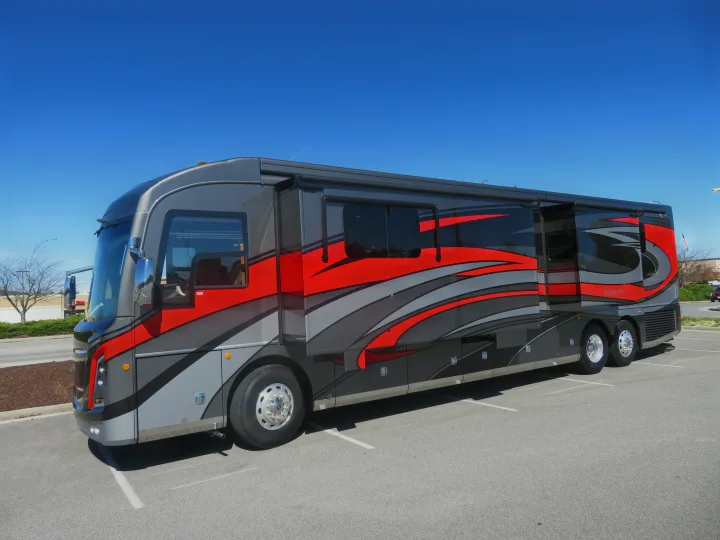 This impressive gray and red Class A motorhome, ideal for an RV rental, is parked with its side extensions out on a sunny day.. Monaco Signature 2019