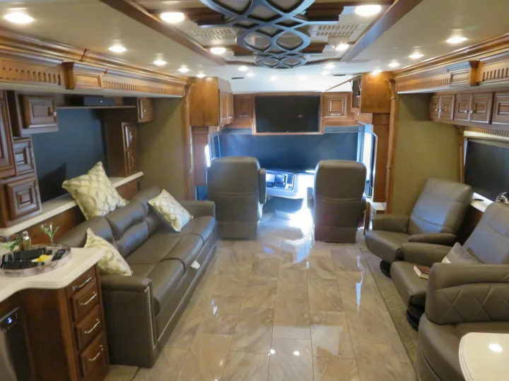 Luxury RV rental interior, showcasing plush seating, elegant wood cabinets, large TVs, and a tiled floor.. Monaco Signature 2019