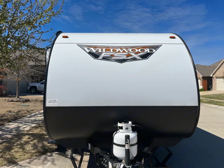 Front of a white and black Wildwood FSX RV trailer with a propane tank. Ideal for an RV rental getaway.. Forest River Wildwood FSX 2022