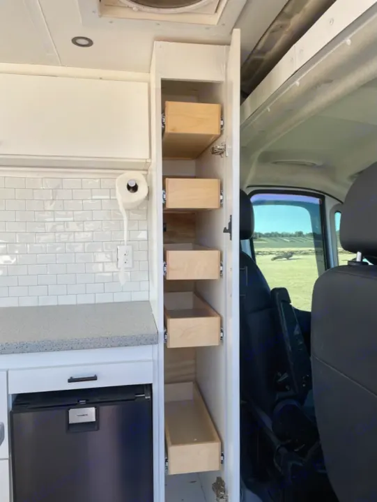 This RV rental interior showcases a compact kitchen with a fridge, tiled wall, and convenient pull-out drawers for ample storage.. Dodge RAM Promaster 2500 2019