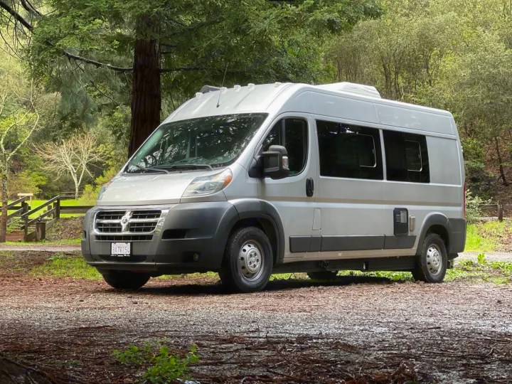 Silver camper van at a wooded campsite, ready for an RV rental adventure. License plate: CA BX77T54.. Hymer Sunlight Van 1 2018