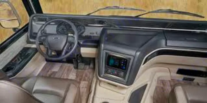View of an RV rental's modern cockpit, featuring a steering wheel, digital dash, and wood-look floor, ready for travel.. Jayco Precept Prestige 2021