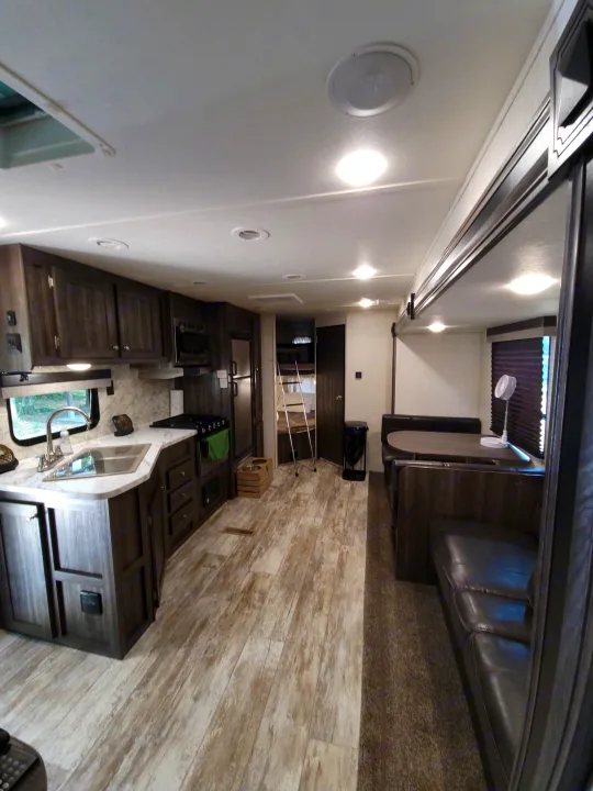 Spacious rv rental interior featuring a full kitchen, dining booth, comfy sofa, and bunk beds. Modern, wood-look design.. Highland Ridge RV Open Range Conventional OT26BHS 2019
