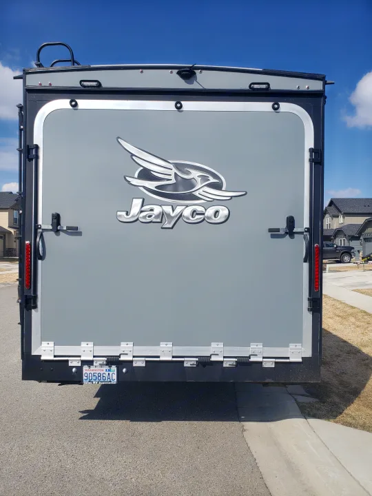 Rear of a grey Jayco toy hauler RV, great for rv rental. Shows ramp door, ladder, and camera.. Jayco Octane 2019