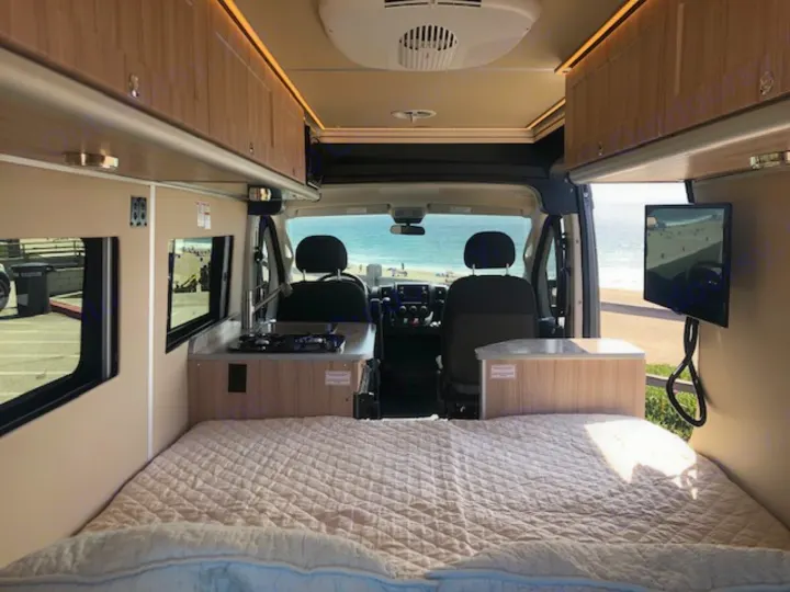 RV rental's interior features a comfy bed, kitchen, and TV. Enjoy the ocean view from this mobile adventure van.. Carado Carado Class B 2018