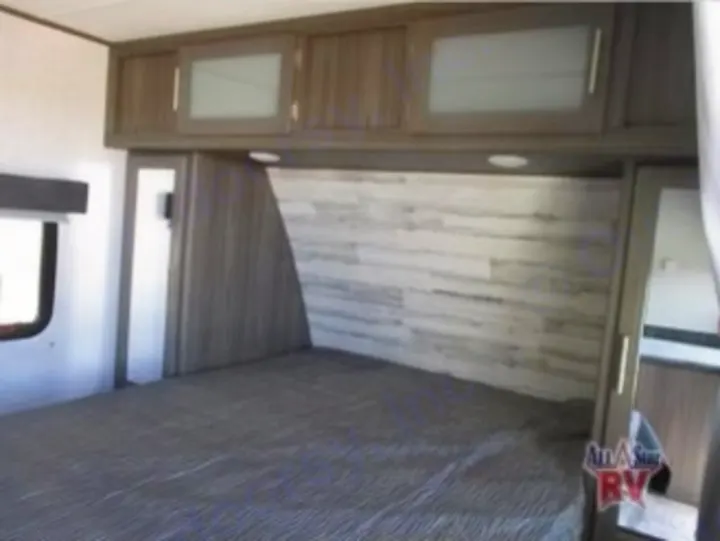 Experience comfort in this RV rental bedroom featuring a large bed, stylish wood-paneled headboard, and ample overhead storage.. Dutchmen Kodiak Ultra Lite 2020