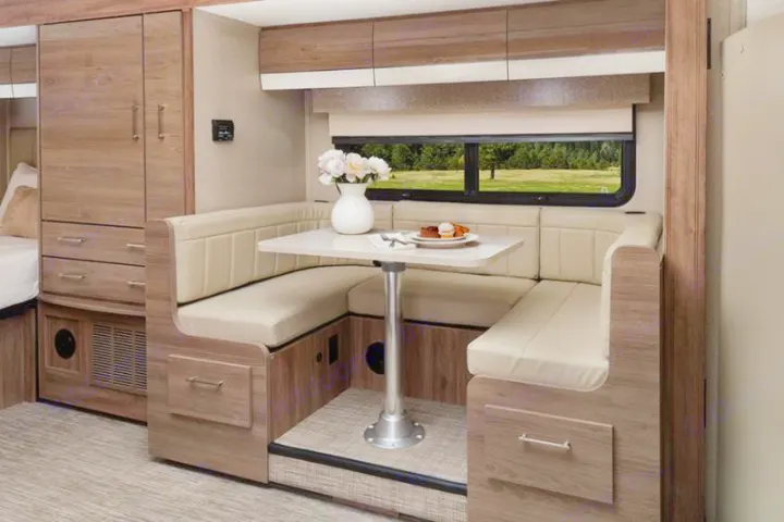 Comfortable RV rental dinette with U-shaped seating, storage, and a view. Enjoy meals on your next adventure!. Entegra Coach Qwest 2020