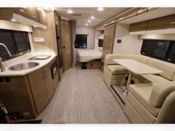 Explore this RV rental's inviting interior: compact kitchenette, U-shaped dinette, and rear bedroom.. Entegra Coach Qwest 2020