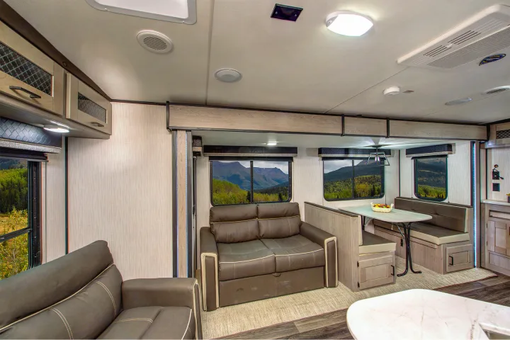 Spacious and modern RV rental interior featuring a comfortable living area, dining booth, and scenic mountain views. Perfect for travel adventures.. Heartland RVs Mallard 2022