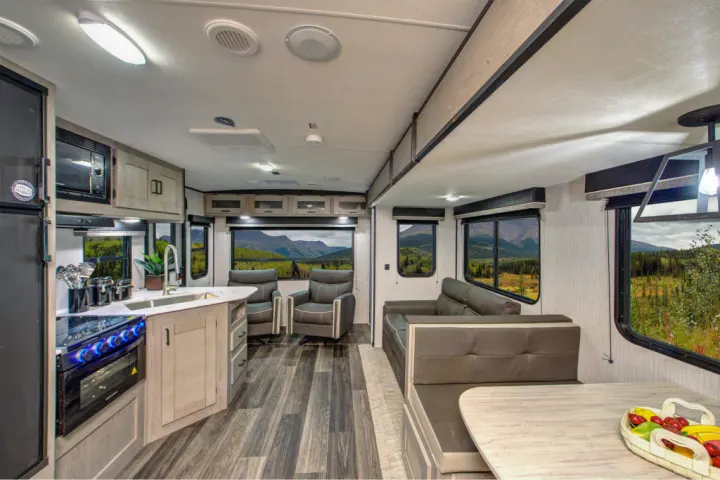 This RV rental interior features a modern kitchen, living area with sofa & chairs, and a dining booth, all with scenic views.. Heartland RVs Mallard 2022