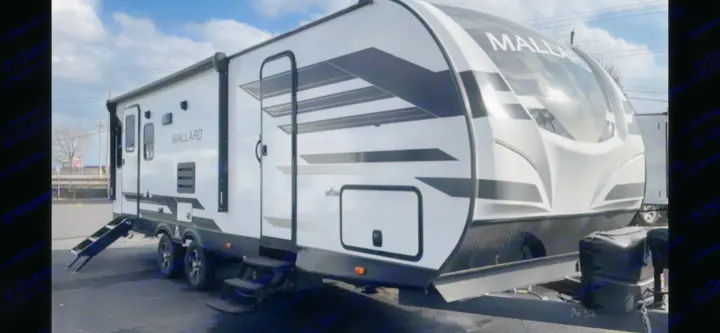 This white and black Mallard travel trailer RV is available for rv rental, parked outdoors.. Heartland RVs Mallard 2022