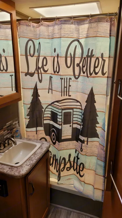 Cozy RV rental bathroom featuring a "Life is Better AT THE Campsite" shower curtain, sink, and mirror.. Thor Freedom Elite 2017