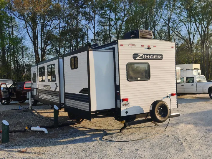 This Zinger RV rental travel trailer is fully set up at a Georgia campsite, with slide-outs extended and utilities connected.. Crossroads RV Zinger 2022
