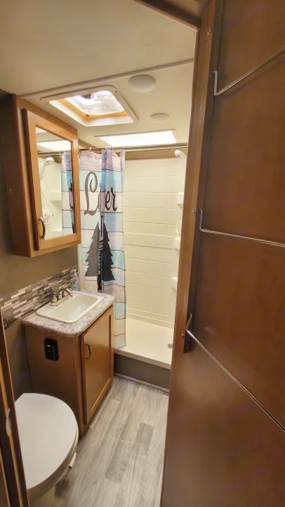 Compact RV rental bathroom featuring a shower, sink, and toilet, offering essential amenities in a small space.. Thor Freedom Elite 2017