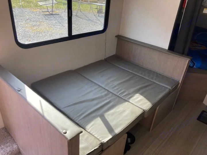 RV rental: Dinette seating converted to a bed in a travel trailer interior, brightened by a window.. Keystone RV Hideout 2021