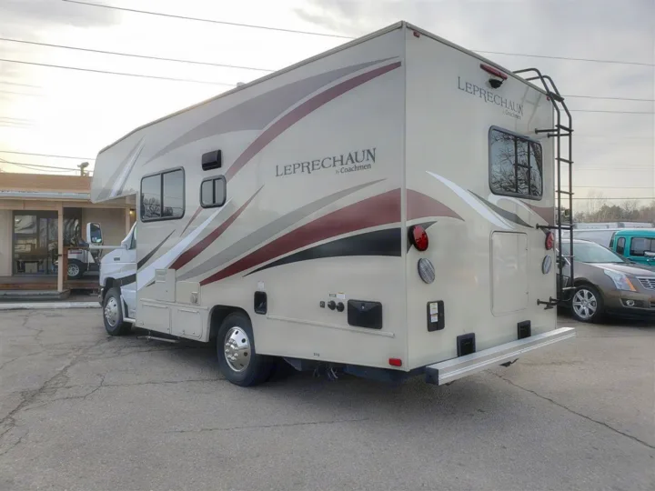 A cream-colored Leprechaun by Coachmen RV, suitable for rv rental, parked on asphalt. Features rear ladder and storage.. Forest River Coachmen Leprechaun 2017