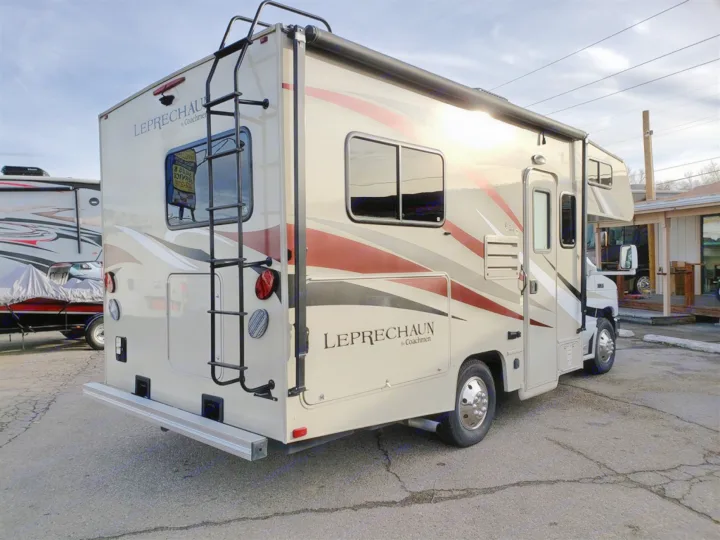 A tan Leprechaun Coachmen Class C RV rental, featuring a rear ladder and side awning, parked on an asphalt lot.. Forest River Coachmen Leprechaun 2017