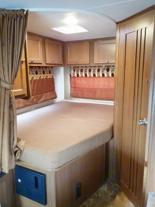 Explore this RV rental's cozy bedroom, featuring a large bed, overhead cabinets, and a side closet.. Forest River Coachmen Leprechaun 2017