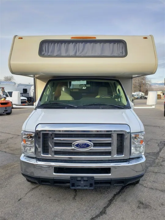 Front-facing white Ford Class C RV, an ideal rv rental option, parked outdoors.. Forest River Coachmen Leprechaun 2017