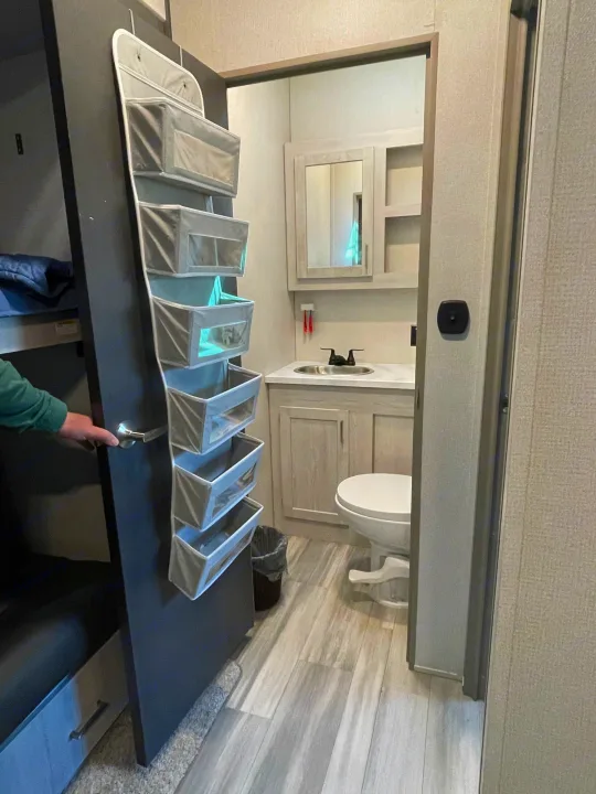rv rental: Efficient RV layout with a compact bathroom and a panel featuring hanging storage by bunk beds.. Keystone RV Sprinter 2021