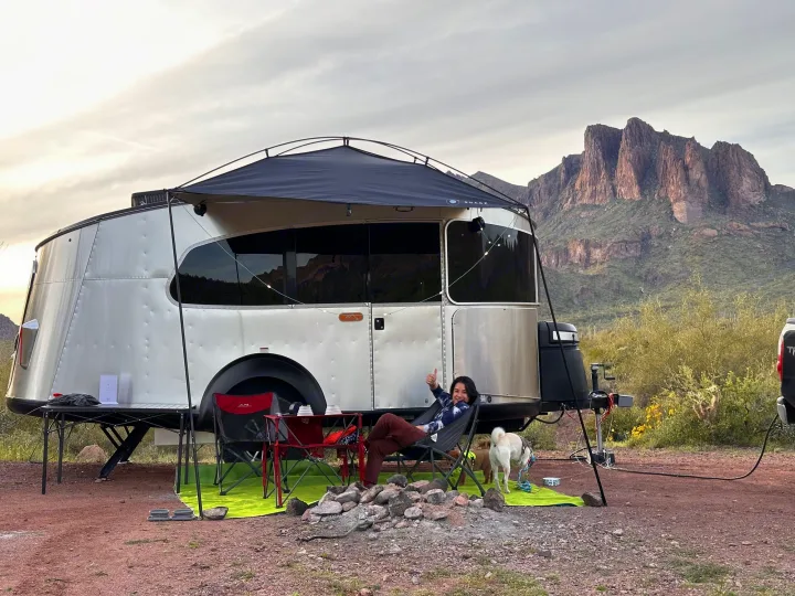 Enjoying a serene desert RV rental experience with mountain views and a cozy setup, complete with a furry friend.. Airstream Basecamp 2021