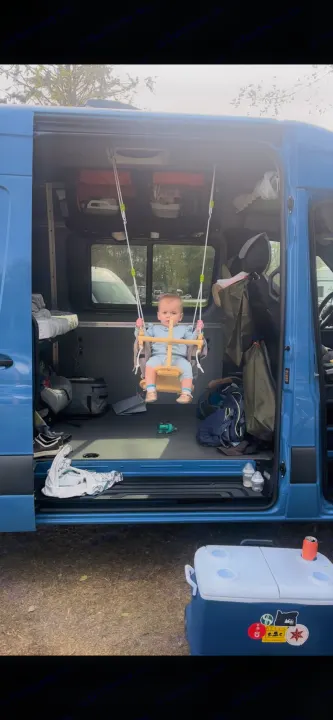 Little one swings inside a blue RV rental van, showcasing family-friendly travel. Perfect for van life adventures!. Mercedes-Benz Sprinter 2021