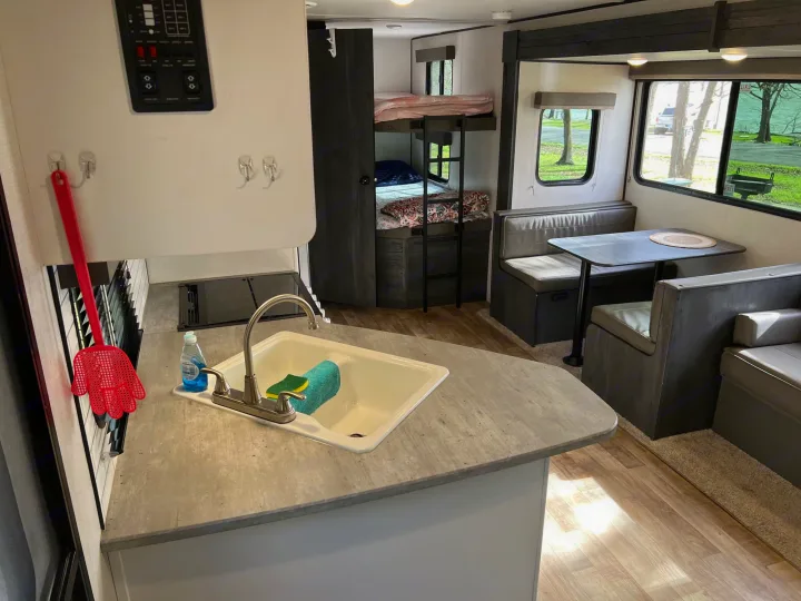 Modern RV rental interior featuring a kitchen with sink, comfortable dinette, and bunk beds for extra space.. Keystone Hideout 2022