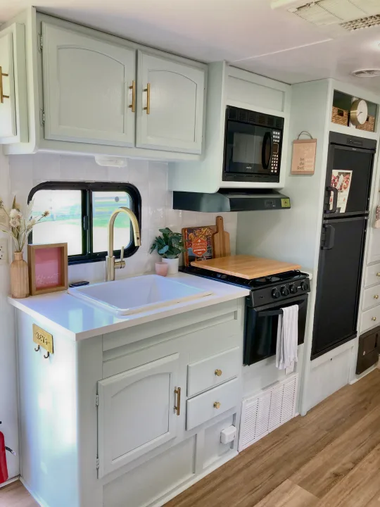 Renovated RV rental kitchen: mint cabinets, white counters, gold accents, sink, microwave, stove, fridge. Functional and stylish.. Other Other 2013