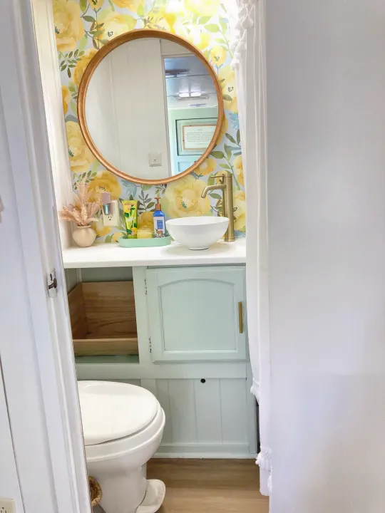 Cozy RV rental bathroom showcases yellow floral wallpaper, a modern vessel sink, and gold-toned faucet and mirror frame.. Forest River Other 2013