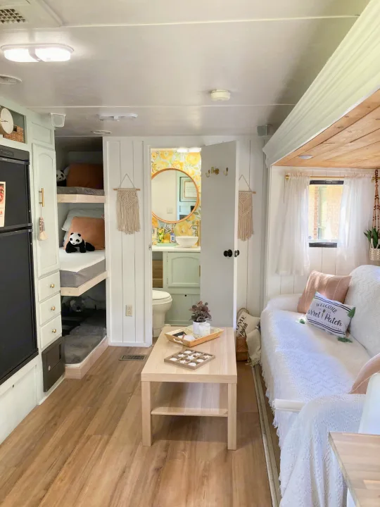 Stylish **RV rental** interior: white living area with couch, light wood floor, bunk beds, and a bright bathroom with yellow wallpaper.. Forest River Other 2013