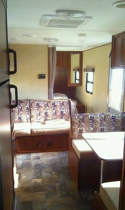 RV rental interior: patterned dinette, sofa with bunk option, fridge, wood cabinets, and AC unit for comfort.. Avenger LT 2012