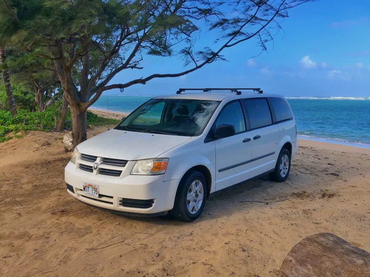 White rental minivan on a Hawaii beach, offering RV rental convenience for island adventures.. Dodge Grand Caravan 2010