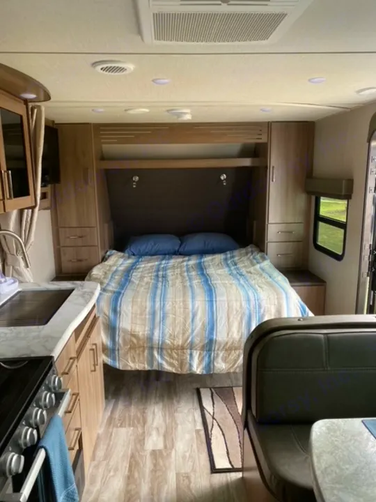 Explore this compact RV rental interior: comfortable bed, equipped kitchen, and dining booth. Ideal for road trips.. Grand Design 21BHE 2023
