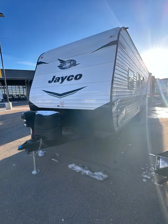 This Jayco travel trailer, ideal for your next RV rental, is parked outside on a sunny day with patches of snow.. Jayco Jay Flight SLX 2022