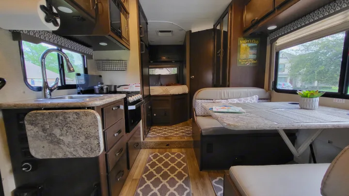 Tour this RV rental's inviting interior with a full kitchen, dinette, and rear bedroom. Wood tones, light counter.. Thor 22HE 2019