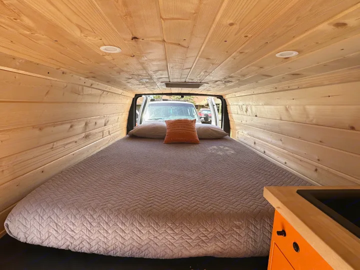 Inside this camper van RV rental, enjoy a comfortable bed, warm wood paneling, and a compact kitchen.. Ford Extended E350 2011