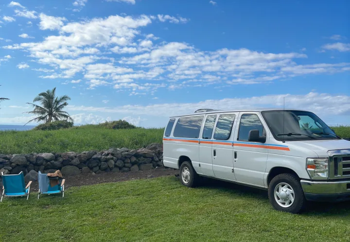 Enjoy a beach getaway! White RV rental van parked on green grass by the ocean, with chairs & palm tree.. Ford Extended E350 2011